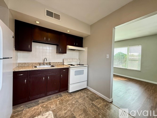 A kitchen with dark brown cabinets and a white stove top oven.