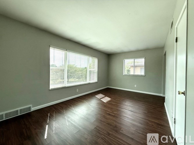 A room with wooden floors and a window with blinds.