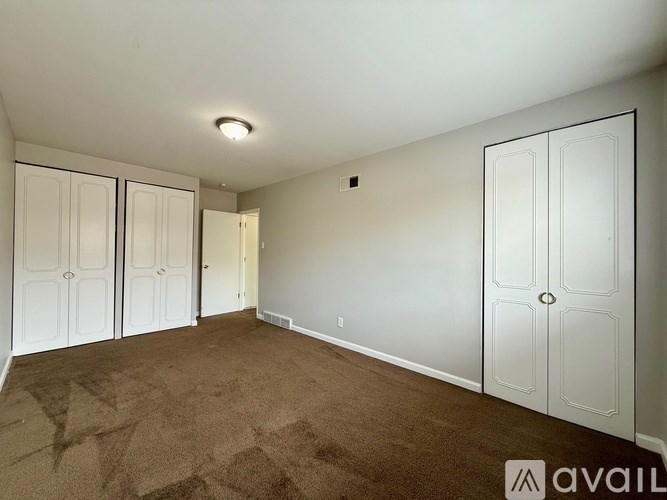 A room with white doors and carpeted floor.
