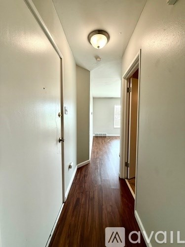 A hallway with a wooden floor and white walls.