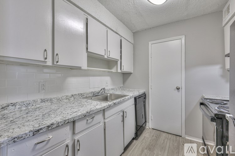 A kitchen with white cabinets and a marble countertop.