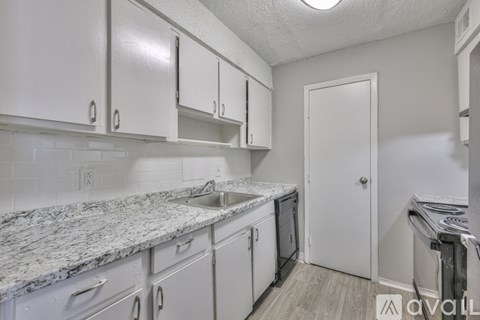 A kitchen with white cabinets and a marble countertop.