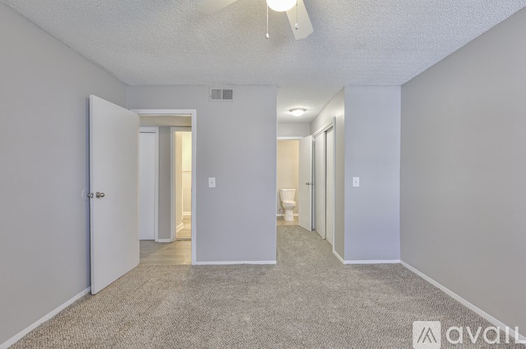 A carpeted hallway with a door on the left and a window in the distance.