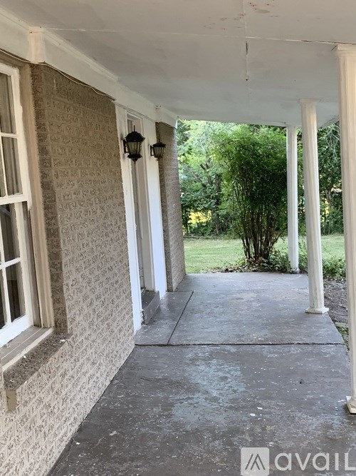 A porch with a white railing and a wall with a patterned design.