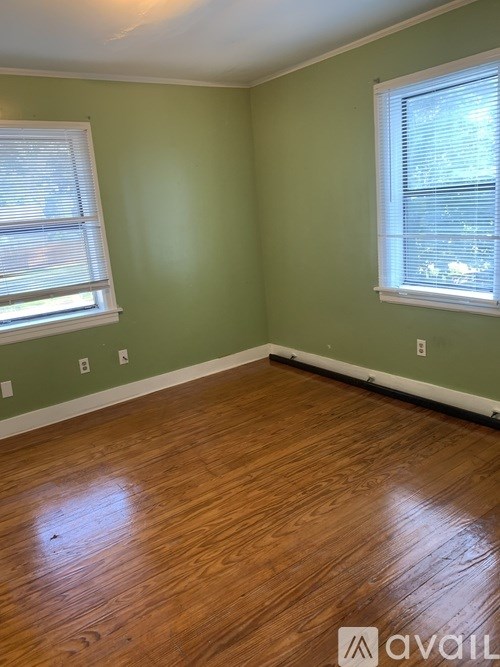 A room with wooden floors and two windows.