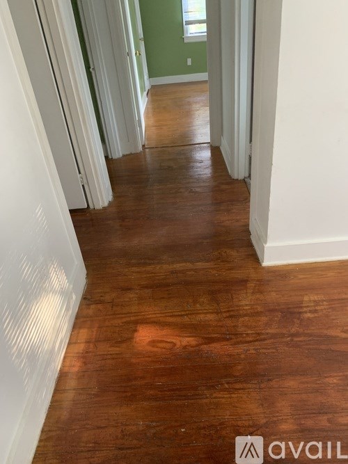 A hallway with wood floors and white walls.
