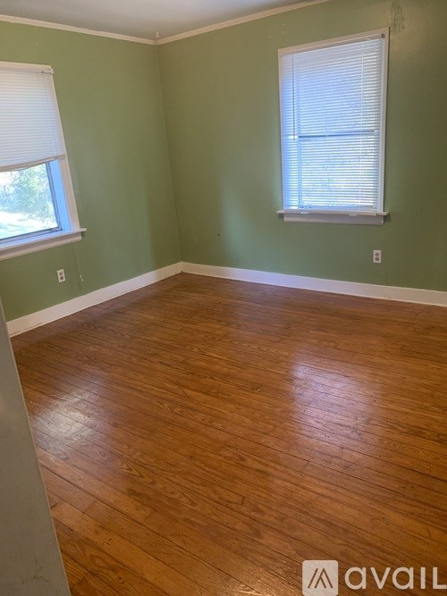 A room with wooden flooring and a window with blinds.
