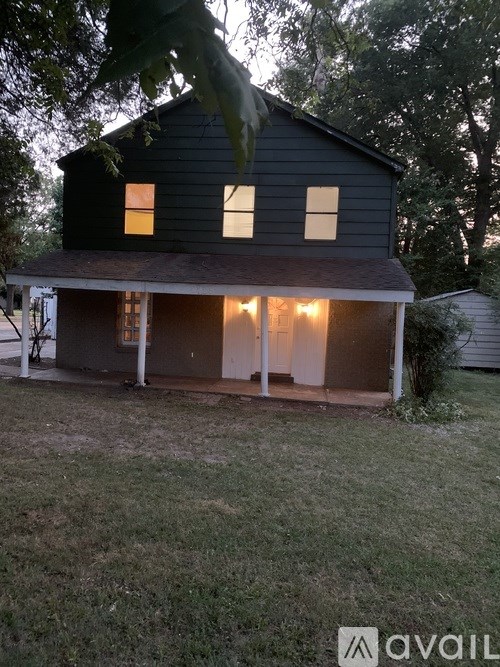 A house with a dark grey exterior and a white porch is shown.