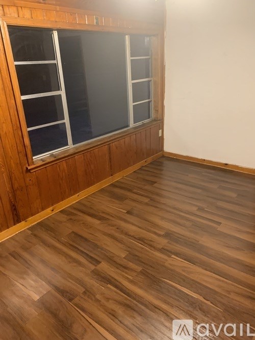 A room with wooden flooring and a window.