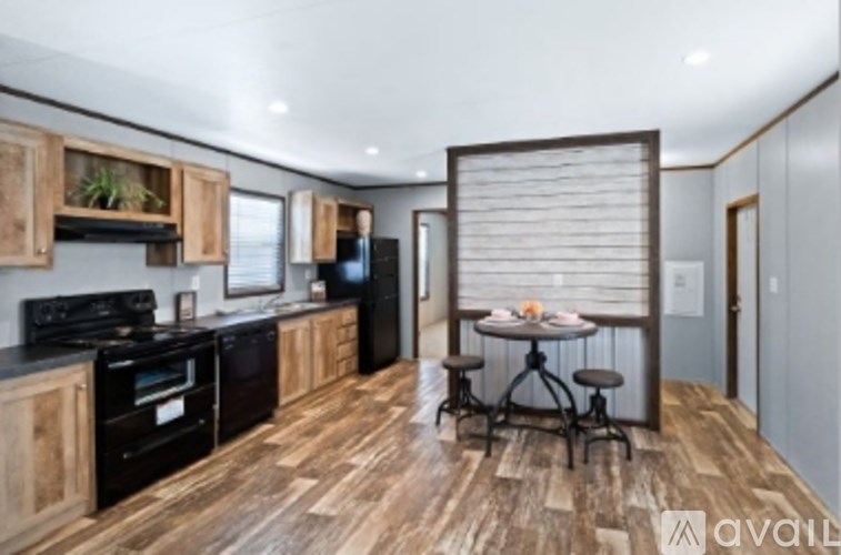 A kitchen with wooden floors and black appliances.