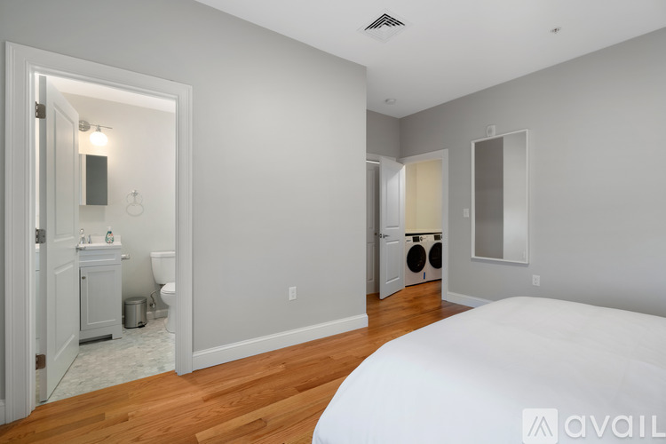 A bedroom with a large bed and a bathroom with a mirror and sink.