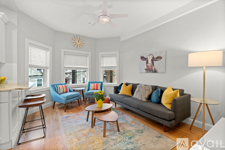 A living room with a grey couch, a yellow table, and a painting of a cow on the wall.