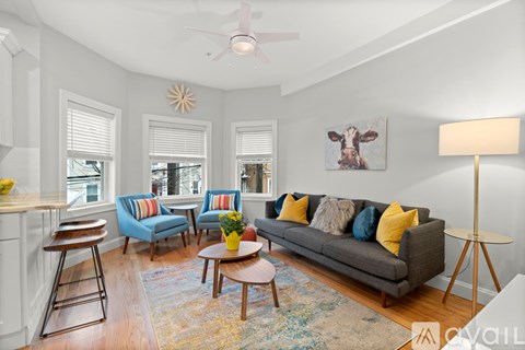 A living room with a grey couch, a yellow table, and a painting of a cow on the wall.