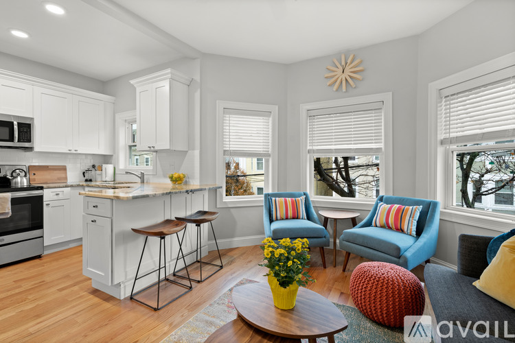A kitchen with white cabinets and a wooden island with bar stools.
