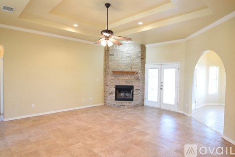 A spacious room with a fireplace and a ceiling fan.