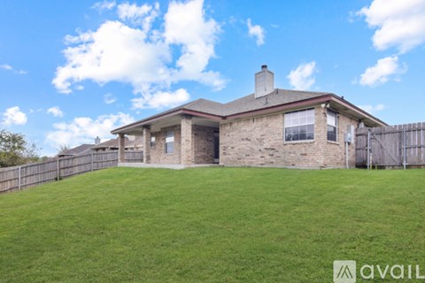 A house with a brown roof and a chimney is surrounded by a grassy area.