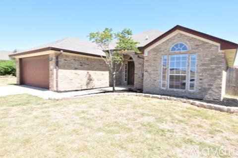 A house with a brown garage door and a tree in front.