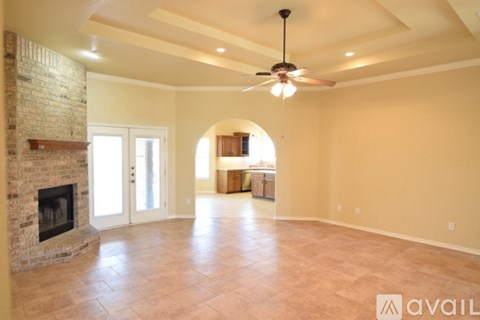 A spacious room with a fireplace and a ceiling fan.