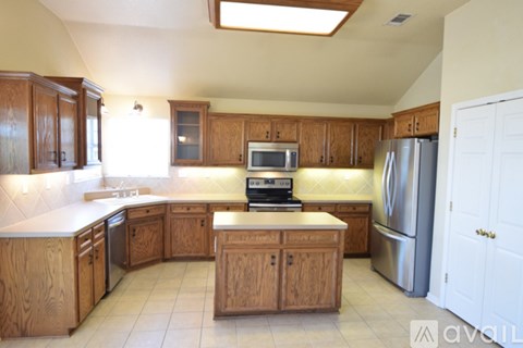 A kitchen with wooden cabinets and a stainless steel refrigerator.