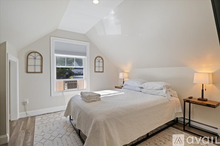 A bedroom with a bed, a window with a view, and a lamp on a side table.