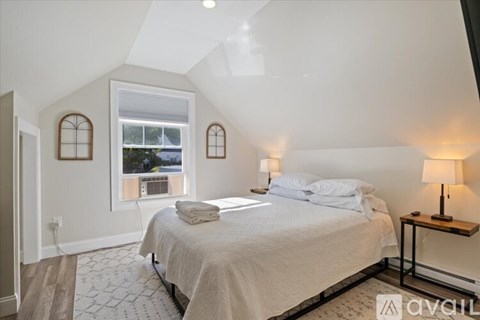 A bedroom with a bed, a window with a view, and a lamp on a side table.