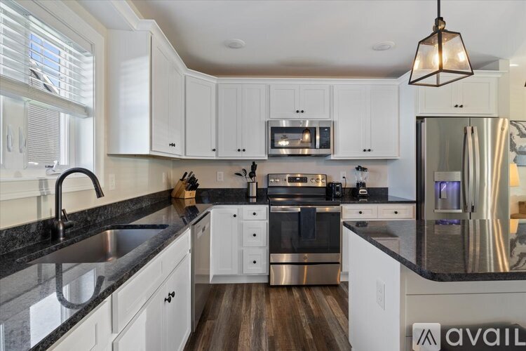 A modern kitchen with white cabinets and a black countertop.