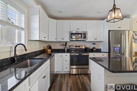 A modern kitchen with white cabinets and a black countertop.
