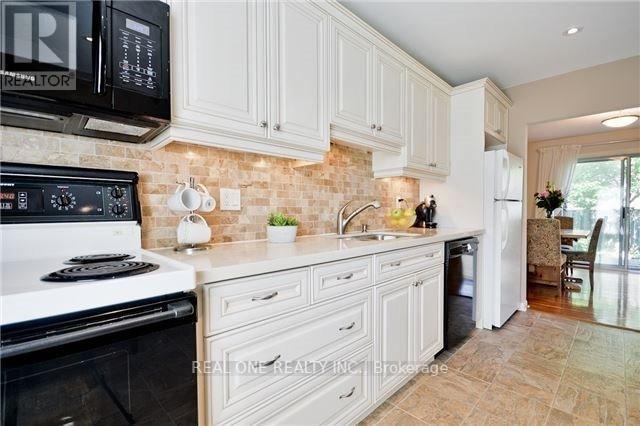 A kitchen with white cabinets and a black microwave.