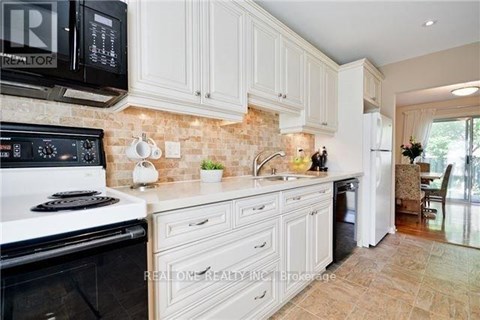 A kitchen with white cabinets and a black microwave.