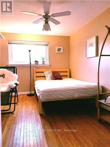 A bedroom with a bed, a chair, and a ceiling fan.