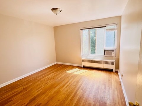 A room with wooden flooring and a window with blinds.