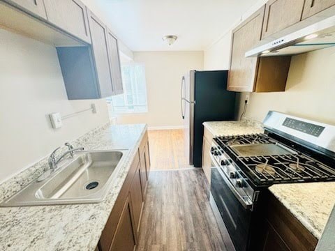 A kitchen with a black refrigerator and a stove top oven.