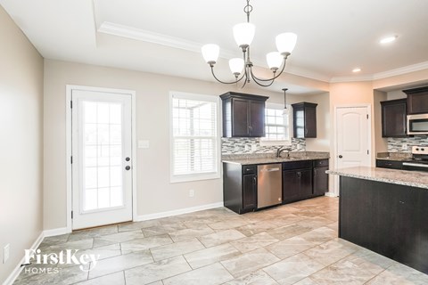 A kitchen with a tile floor and a chandelier hanging from the ceiling.