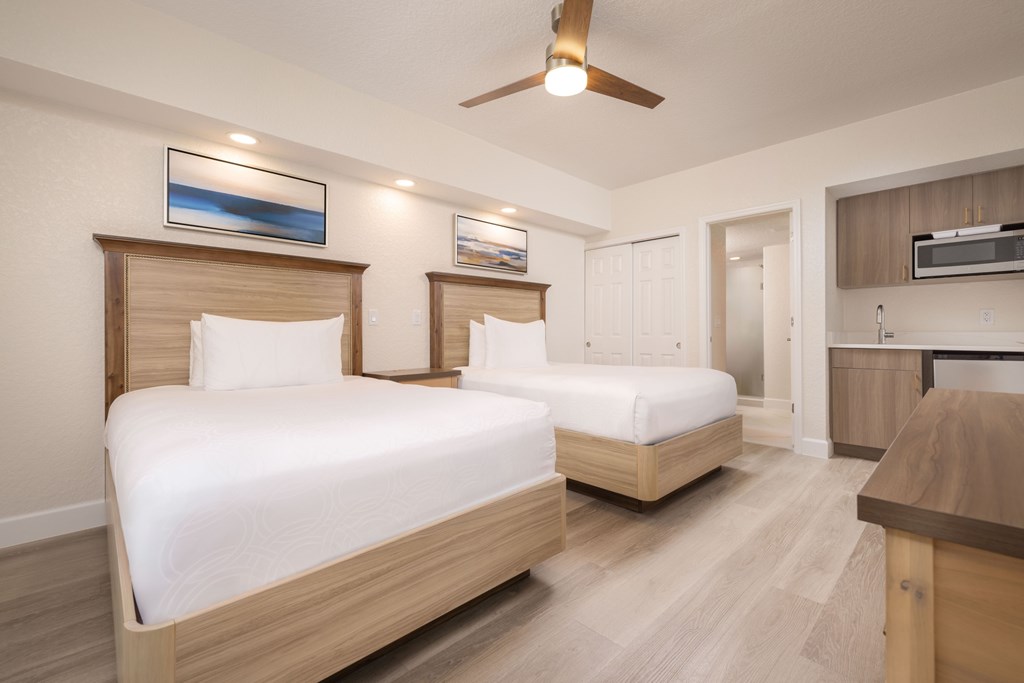 Two beds in a room with a ceiling fan.