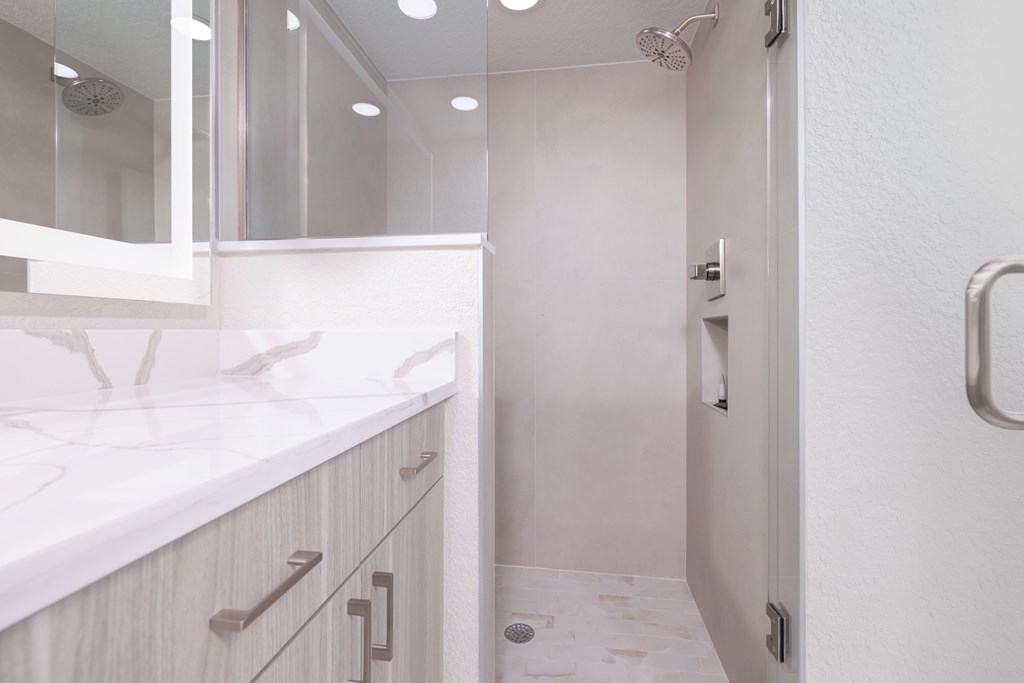 A white bathroom with a sink and a shower.