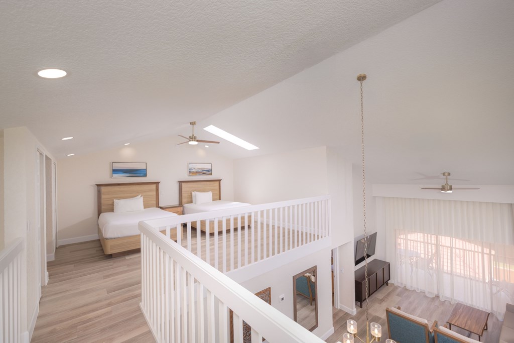 A white baby crib is in the middle of a room with two beds.