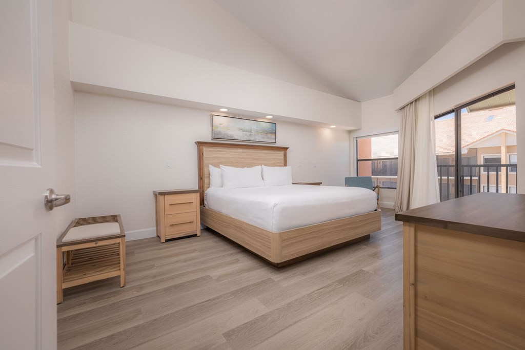 A bedroom with a large bed, nightstand, and chair.