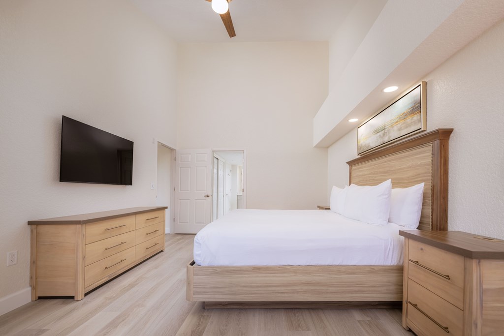 A bedroom with a bed, dresser, and tv.