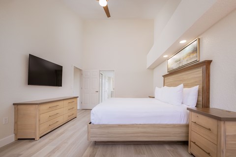 A bedroom with a bed, dresser, and tv.