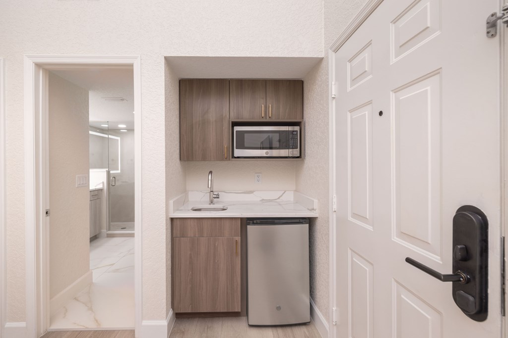 A small kitchen with a sink, microwave, and trash can.