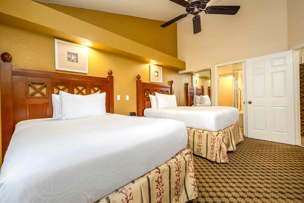 Two beds in a room with a ceiling fan.