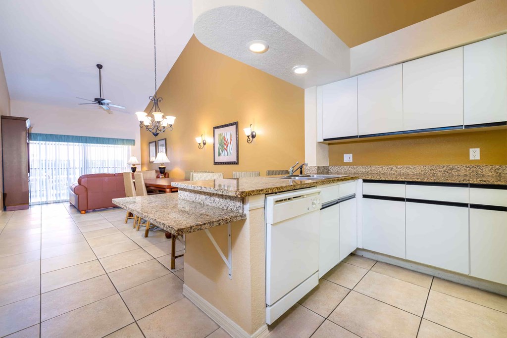 A kitchen with a marble island and white cabinets.