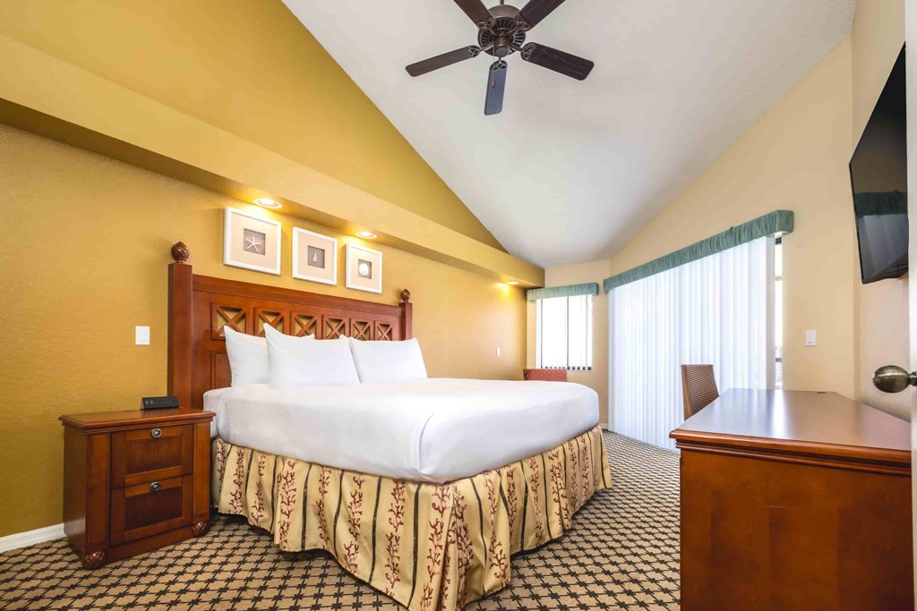 A bedroom with a bed, nightstand, and a ceiling fan.