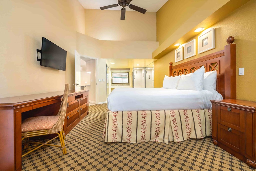 A hotel room with a large bed, a chair, and a television.