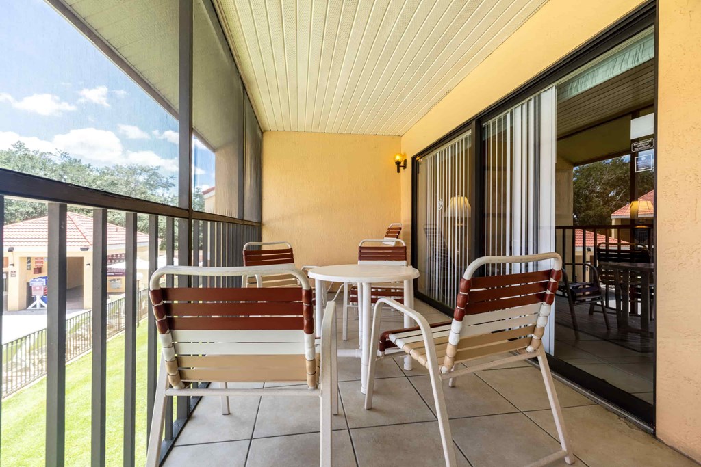 A patio with a table and chairs overlooking a lawn.