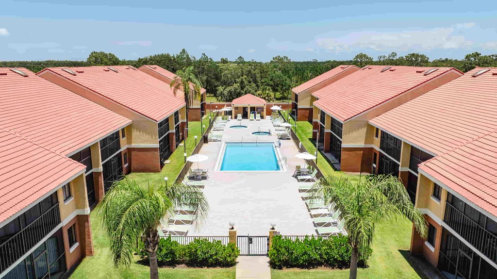 A view of a pool surrounded by buildings and palm trees.