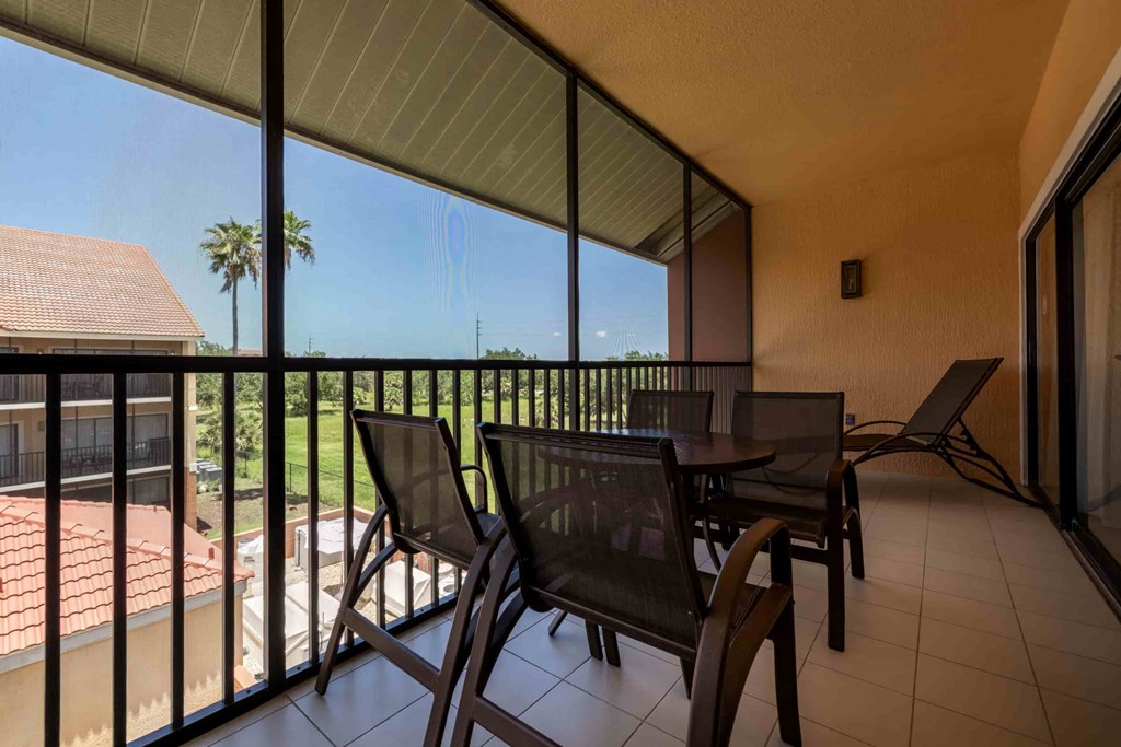 A patio with a table and chairs overlooks a green lawn.