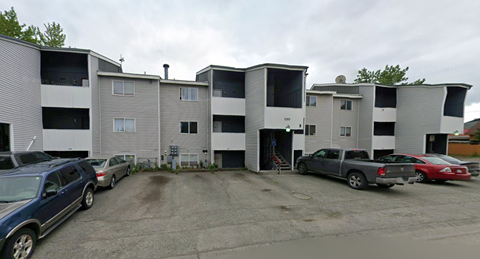 A parking lot with cars and apartment buildings.