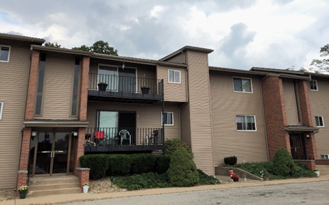 A two-story apartment building with a balcony on the first floor.