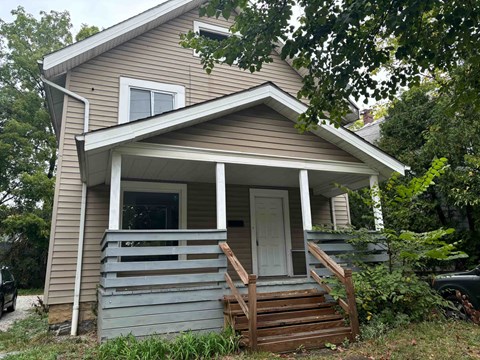 A small house with a porch and a white door.